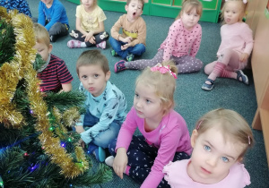 Dzieci oglądają pięknie ubrane drzewko.