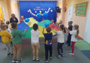 "Biedronki" bawią się wesoło z chusta animacyjną i balonami.