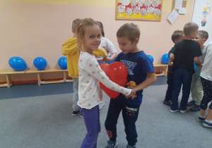 Marysia i Kacper tańczą z balonem.