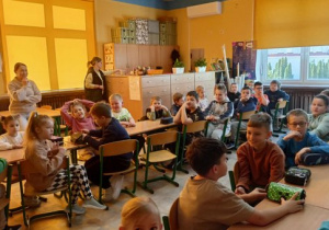 Biedronki razem ze starszymi kolegami siedzą w szkolnych ławkach.