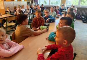 Biedronki razem ze starszymi kolegami siedzą w szkolnych ławkach.
