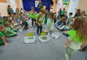 Hania wraz z kolegami ze starszych grup segreguje śmieci do odpowiednich pojemników.
