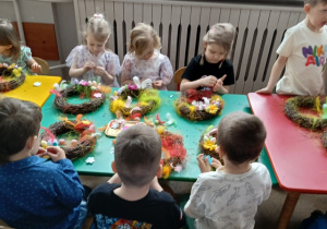 Dzieci wykonują wianki wielkanocne.