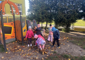 Dzieci zbierają jesienne liście.