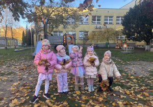 Dziewczynki prezentują swoje jesienne bukiety z liści.