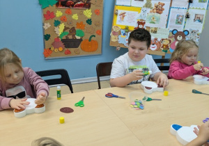 dzieci przyklejają elementy misia