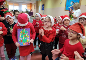 Dzieci wręczają mikołajowi upominek.