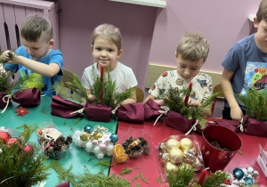 Dzieci tworzą stroiki bożonarodzeniowe.