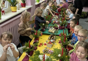 Dzieci ozdabiają stroiki bombkami.
