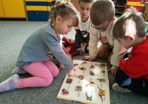 Dzieci oglądają książki o dinozaurach.