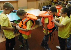 dzieci pomagają sobie podczas zakładania kamizelek ratunkowych