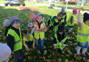 Dzieci bawią się kolorowymi liśćmi.