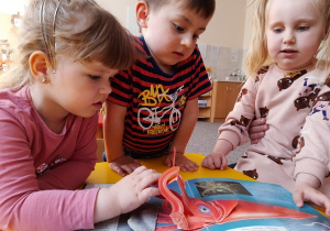 Dzieci oglądają wypożyczoną z biblioteki książkę