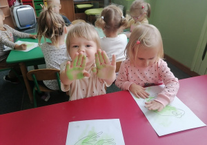 Nel pokazuję rączki które ciężko pracują malując a Laura ze skupieniem maluje swoją prace „żabkę”.