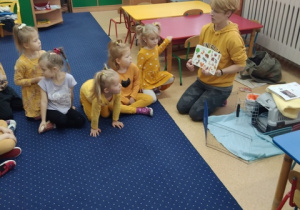 Dzieci oglądają ilustrację zwierząt leśnych.
