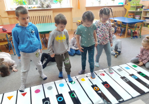 Gabrysia, Laura, Gabryś i Mikołaj grają fragment utworu stopami.