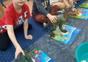 Przedszkolaki wykonują odcisk łapy dinozaura w masie solnej.
