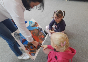 Dziewczynki oglądają ilustrację tematyczną.