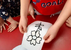 Chłopiec układa obrazek kwiatka na talerzu.