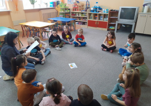 Biedronki siedzą na dywanie słuchają opowiadania.