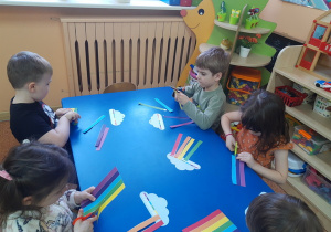 Dzieci wycinają kolorowe paski tęczy.