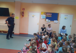 Pan Policjant opowiada dzieciom o zasadach bezpieczeństwa podczas wypoczynku wakacyjnego.