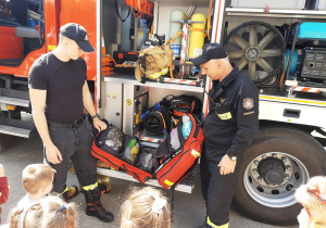 Strażacy tłumaczą do czego służy apteczka pierwszej pomocy, zznajdująca się na wyposażeniu wozu strażackiego.