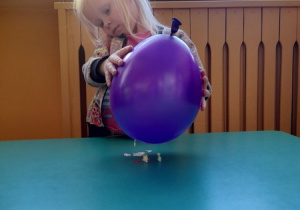Dziewczynka przeprowadza doświadczenie z balonem.