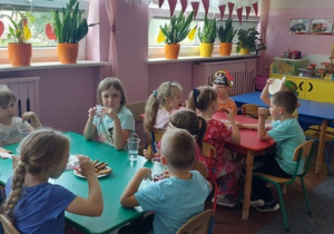 Dzieci przy stolikach - słodki poczęstunek i miłe rozmowy.