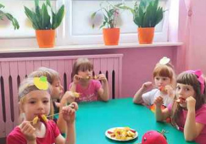 Dzieci jedzą szaszłyki z jabłek.