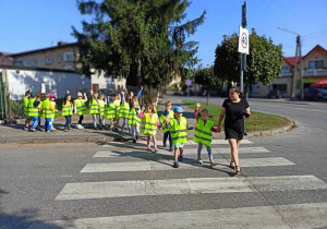 Dzieci przechodzą przez jezdnię zachowując zasady bezpieczeństwa.