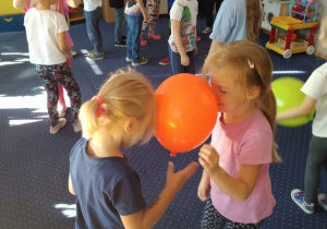 Sonia i Julka tańczą trzymając balon głowami.