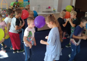 Dzieci tańczą trzymając balony głowami.